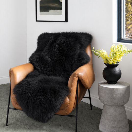 Black sheepskin runner draped over a tan leather armchair